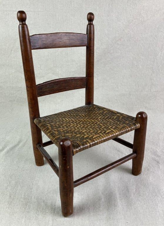 Small Country Chair: Small country chair ideal for decorative display, featuring a rivercane-style seat and classic ladder-back construction. Sturdy form with a rich dark patina and turned finials. Measures approximately