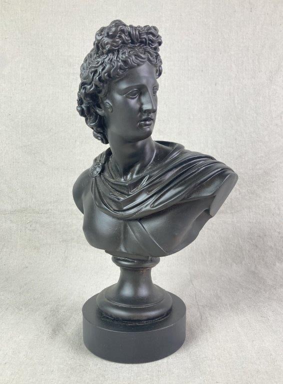 Bust of Apollo: Polyresin bust of the Greek and Roman god Apollo with a smooth black finish, featuring intricate drapery and detailed hair, set on a pedestal and plinth base. Measures approximately 14 1/2" H x 8
