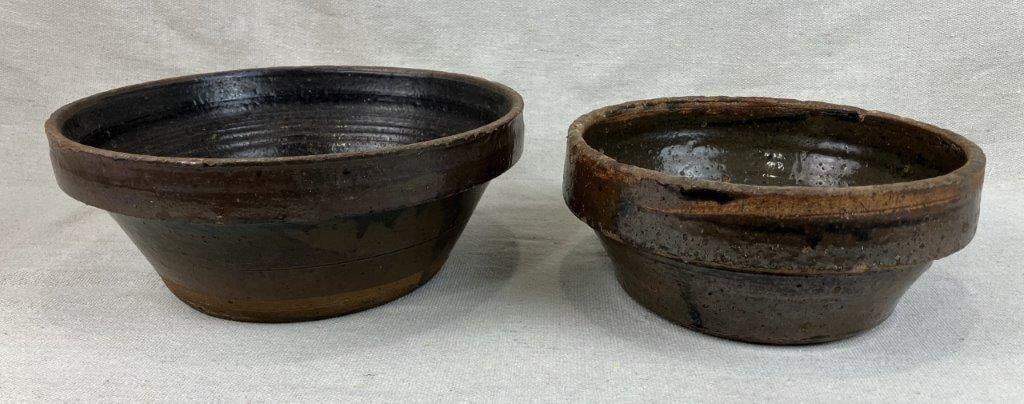 Two Glazed Stoneware Bowls: A pair of hand-crafted ceramic vessels featuring traditional deep-welled forms and finished in rich, lustrous glazes. These bowls exemplify the enduring appeal of stoneware, showcasing the subtle