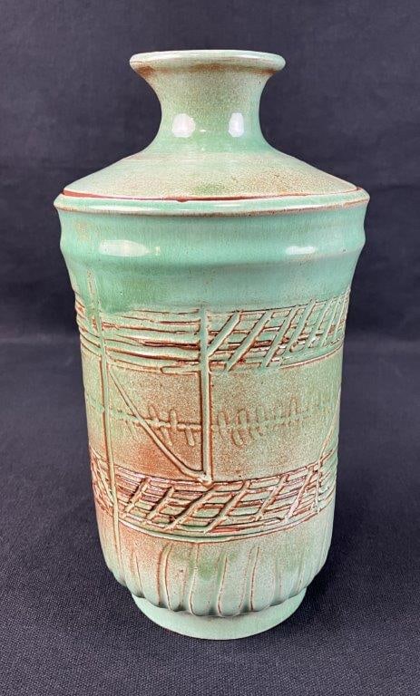 Studio Pottery Celadon Glaze Covered Jar: Lidded vessel with a beautiful celadon glaze over a sienna, red clay body, featuring incised line work throughout. Incised signature on the underside. Measures approximately 9 1/2" H x 5" diameter.