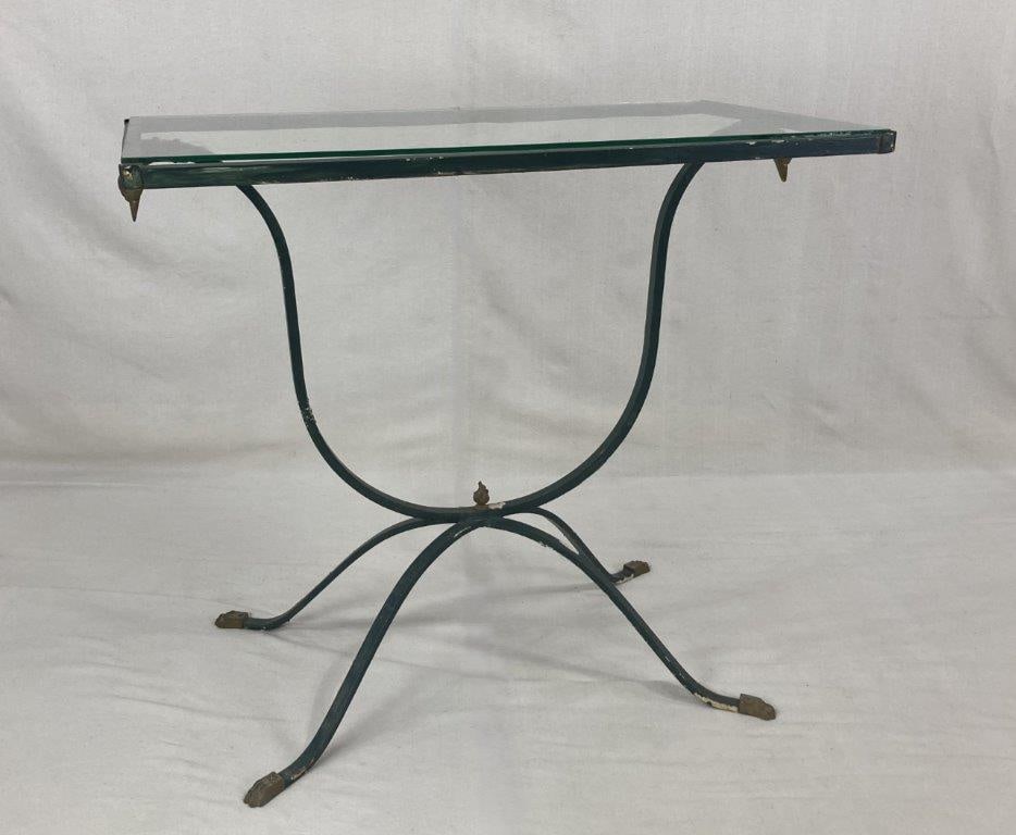 Neoclassical Style Glass Top Table: Neoclassical style table featuring a glass top supported by a polychromed metal base with brass accents. The base displays elegant curving lines with decorative swan head supports and paw form feet,