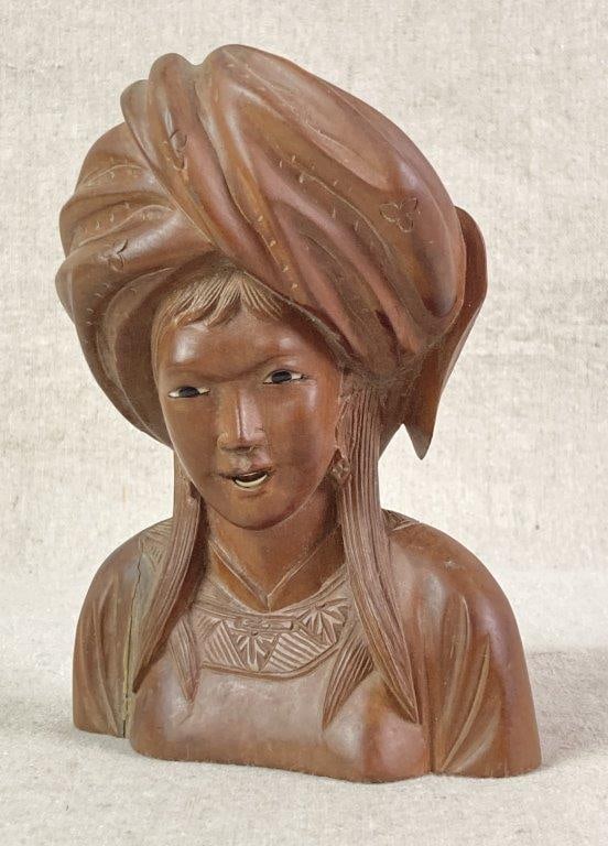 Carved Bust of Balinese Woman: Hand-carved wood bust of a Balinese woman featuring an intricately carved head wrap and expressive facial features. The composition is detailed with incised lines to represent the hair, a geometric