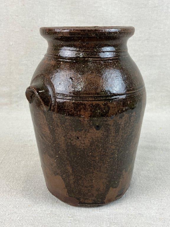Southern Alkaline Glaze Stoneware Jar: Southern stoneware jar featuring a characteristic rounded form with applied lug handle and incised band decoration encircling the body. Finished in a dark alkaline glaze typical of traditional