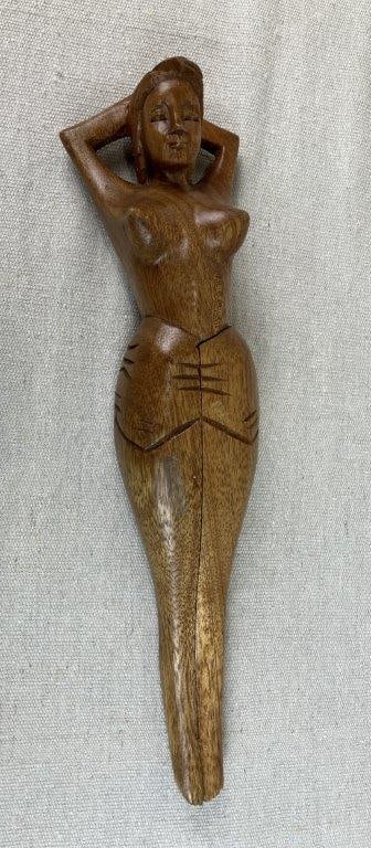 Folk Art Carved Woman Nutcracker: Folk art carved wooden nutcracker depicting a stylized female figure with curving form and incised linear detailing emphasizing the carved craftsmanship. The figure features articulated, movable legs
