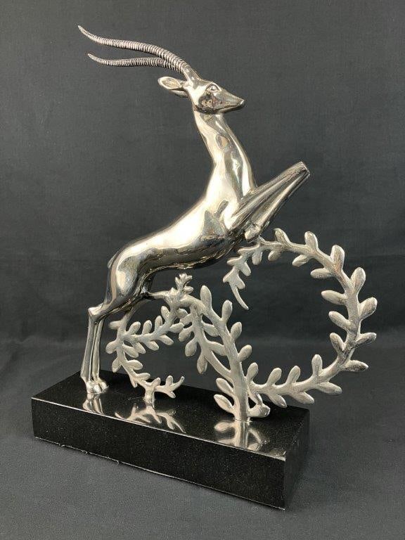 Silvertone Leaping Gazelle Sculpture: Elegant sculpture depicting a leaping gazelle in cast metal with a silvertone finish, rising above swirling leafy vine forms and mounted on a dark base. Measures approximately 18