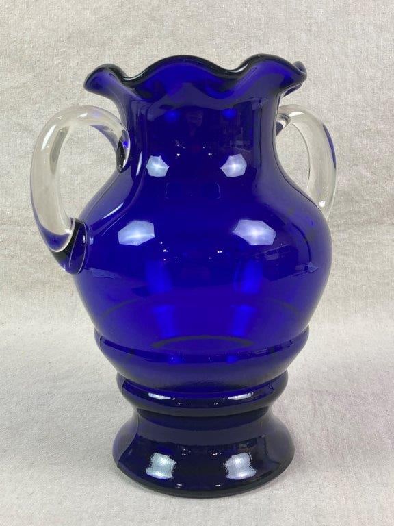 Blue Art Glass Vase: An Art Deco style art glass vase, circa 1930, featuring a deep cobalt blue body with contrasting clear glass handles and a scalloped rim. Measures approximately 10'' H x 8'' W x 6'' D, Good