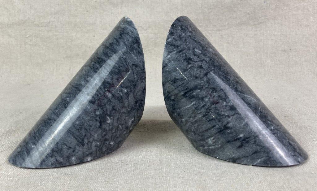 Polished Marble Bookends: marble bookends with a polished appearance and with an angled cylindrical design, One measures approximately 5'' H x 3 1/4'' W x 7'' D, Good condition with light wear. 