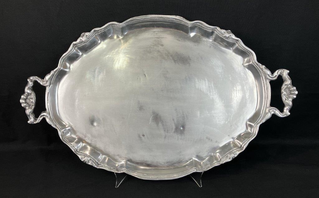 Decorated Aluminum Oval Tray: Classic oval tray with scalloped edges and decorative embellishment in an antique style. Substantial form with two decorated handles. Ideal as a decor accent or for serving. Measures approximately 27