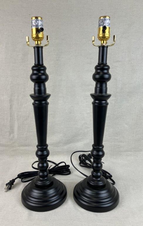 Pair of Black Candlestick Lamps: Metal candlestick-style lamps with a smooth matte black finish, featuring a turned appearance, domed base, and long tapering neck. The lamp with the shade support measures approximately 28