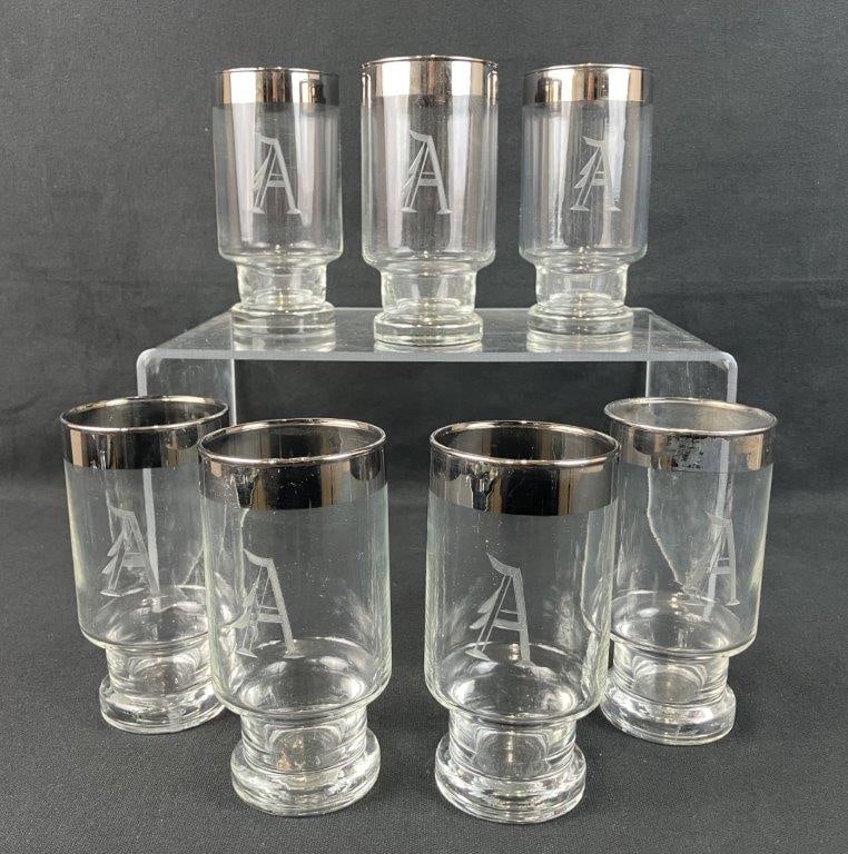 Seven Etched Glass and Silver Rimmed Lowball Glasses: Anchor Hocking Bremen pattern lowball glasses with etched “A” monogram and silver rims. One glass measures approximately 5 1/2″ H x 2 3/4″ diameter. Some wear to the silver