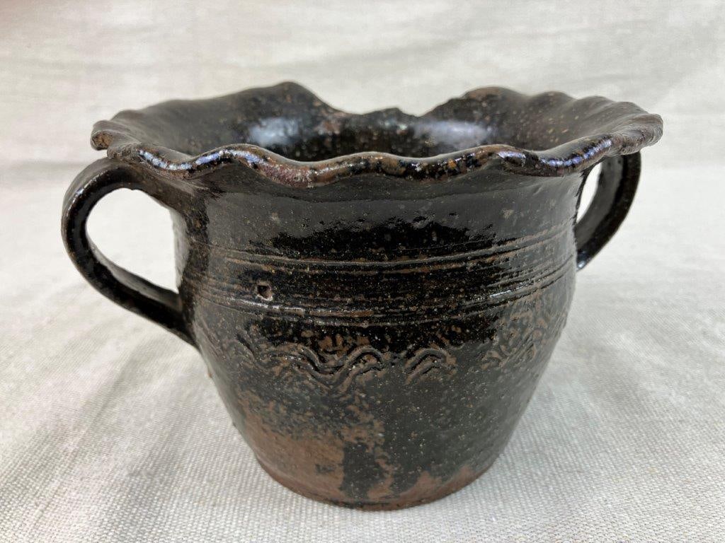 Southern Alkaline Glaze Flower Pot: Stoneware flower pot with a ruffled lip, two applied handles, and incised bands with linear curving designs. Finished in a traditional Southern alkaline glaze with a drainage hole at the base.