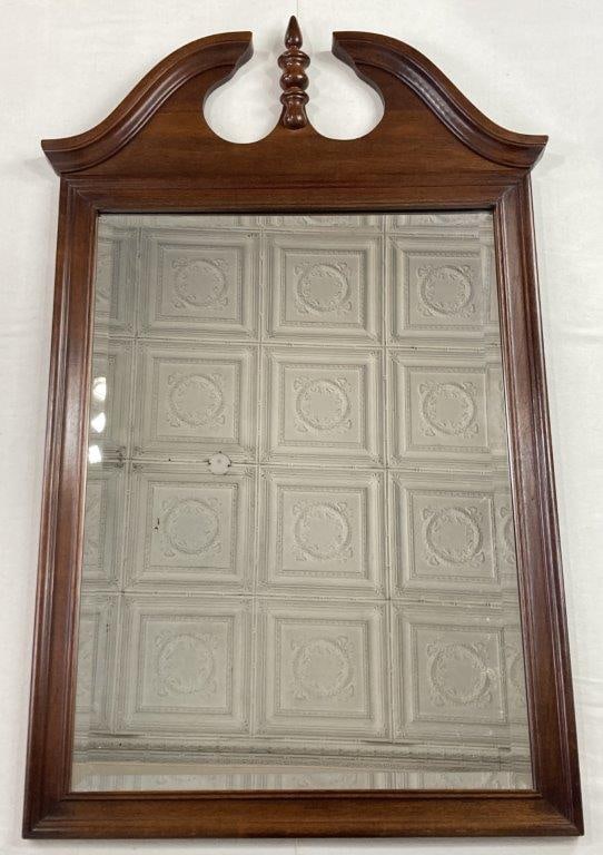 Mahogany Mirror: A stately wall mirror crafted from mahogany featuring a prominent broken pediment top with elegant scrolled detailing and a central turned finial. The frame houses a high-quality beveled glass mirror