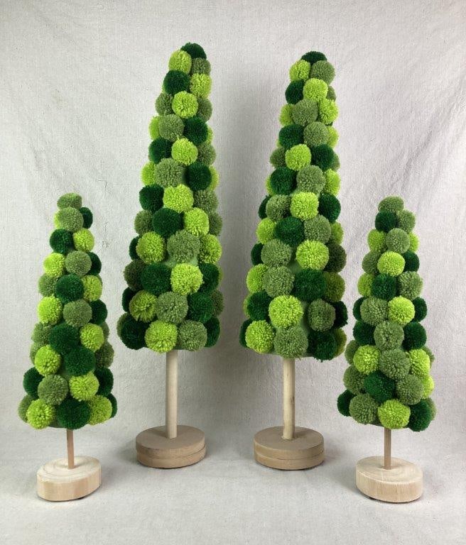 Four Pom Pom Trees: Decorative trees created with varying shades of green pom poms arranged in a conical shape and mounted on round wood bases, including two larger and two smaller examples. One of the larger trees