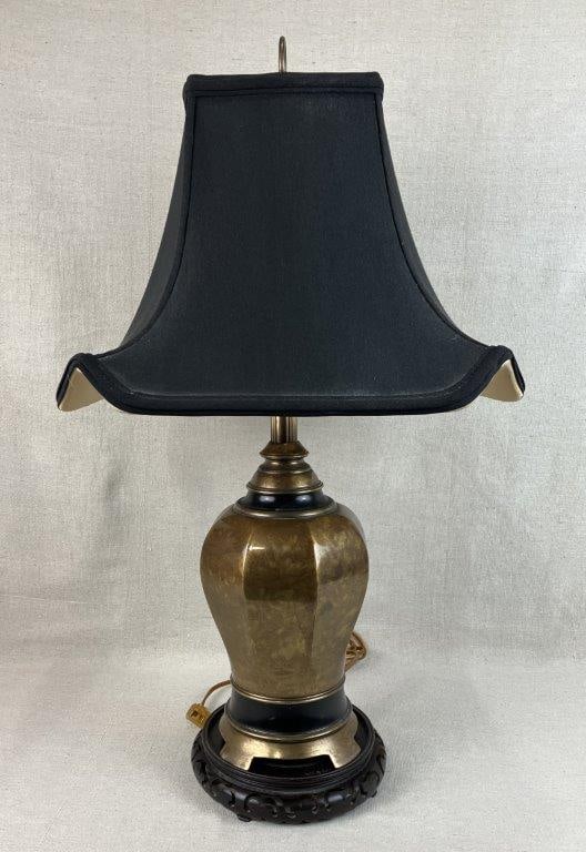 Mid Century Modern Faceted Brass Lamp: Mid Century Modern brass table lamp executed in a faceted ginger jar form, featuring a hexagonal paneled brass body raised on a carved Chinese-style wood base. The lamp is paired with a complementary