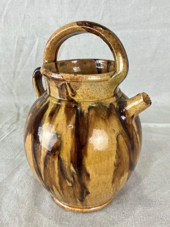 Slip Decorated Pitcher: Earthenware form with a rounded body, decorated in rich sienna and warm brown umber slip. Measures approximately 9 1/4" H x 6" W x 5" D. Chips to spout, otherwise good condition. 