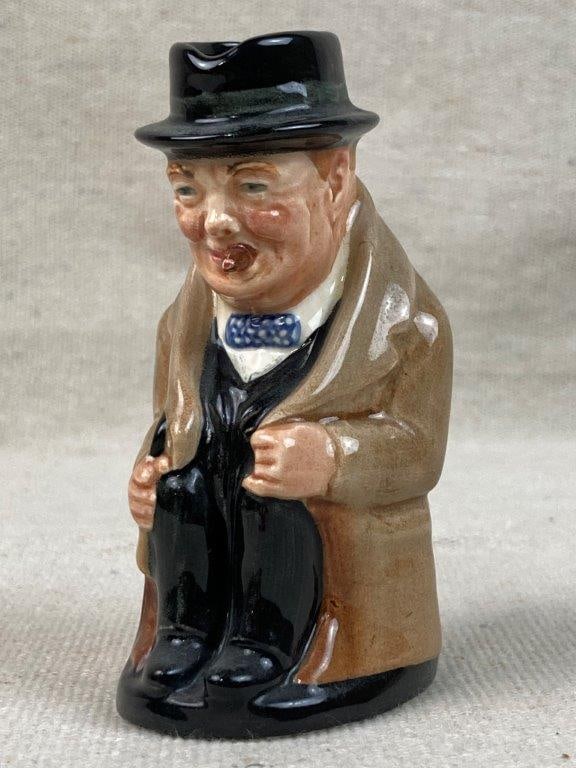 Winston Churchill Royal Doulton Toby Jug: A collectible small English character jug depicting the iconic British Prime Minister. This piece features the whimsical and expressive hand-painted details synonymous with Royal Doulton