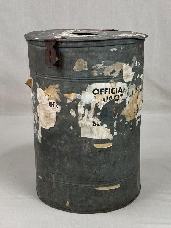 Galvanized Metal Ballot Box: An authentic industrial relic featuring a sturdy cylindrical metal form with a functional slot and lid characteristic of early voting or collection bins. The galvanized finish provides a rugged,