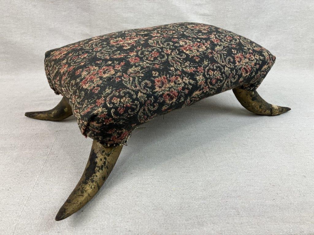 Horn Stool with Floral Upholstery: Folk art foot stool featuring four horn feet with a gilt finish supporting an upholstered seat with floral patterned fabric. The combination of natural horn elements and decorative upholstery creates