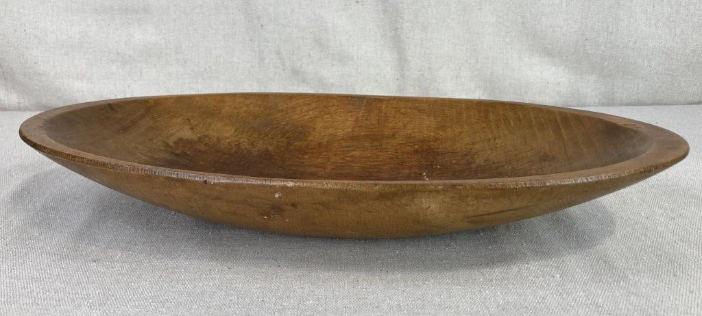 Oval Wood Dough Bowl: This primitive-style dough bowl is hand-carved from a single piece of wood, showcasing a classic elongated form and a rich, warm patina. A functional detail of this piece is the integrated handles
