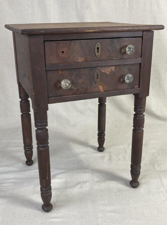 19th Century Mahogany Two-Drawer Stand: A rectangular top over a conforming case fitted with two drawers with dovetail construction, each showcasing highly figured crotch veneer fronts. The drawers are accented by decorative pressed glass