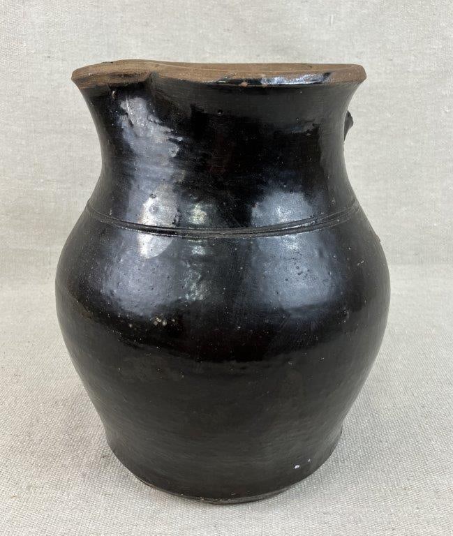 Glazed Stoneware Pitcher: This utilitarian pitcher features a classic rounded form accented by a single incised band defining the upper body and was originally crafted with an applied handle. Finished in a traditional