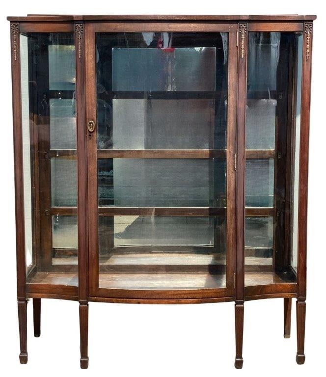 Antique Curio Cabinet: Curio cabinet featuring a mirrored back, glass sides, and a serpentine front, accented with carved gold gilt ribbons and foliage. Measures approximately 59 1/2" H x 49 1/2" W x 18" D. Wear to the