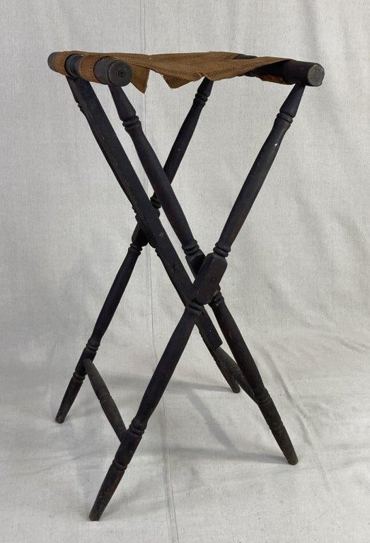 19th Century Luggage Rack: This classic utilitarian piece features a sturdy X-frame construction composed of turned hardwood legs and stretchers finished in a ebonized tone. The top is fitted with two woven fabric straps