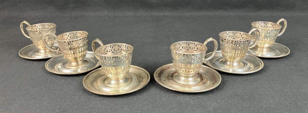 Sterling Silver Demitasse Cup Holders and Saucers: Set of six sterling silver demitasse cup holders with matching saucers by the Webster Company, featuring a reticulated filigree design with floral adornments. Designed to hold porcelain liners, the