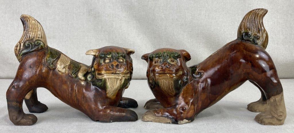 Chinese Pottery Foo Dogs: This unique pair of pottery figures depicts traditional Foo Dogs in an elongated stretching pose. The figures feature deep brown painted bodies, with one specifically highlighted by embossed green and
