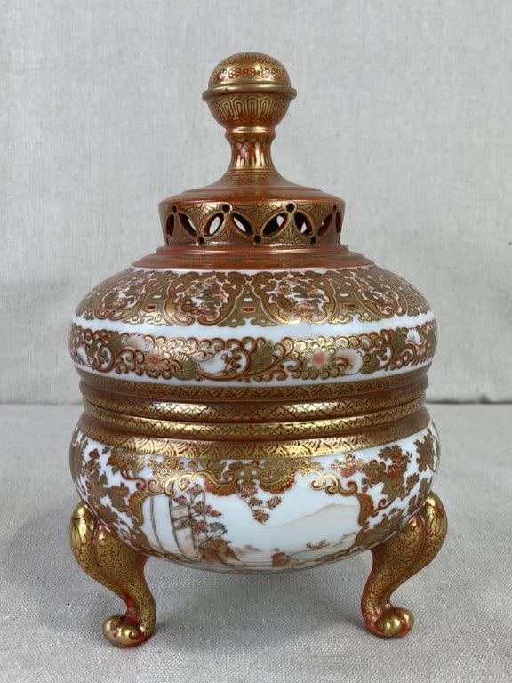 Japanese Satsuma Koro: Ornate tripod incense burner featuring a domed, reticulated cover surmounted by a knopped finial. The body is lavishly decorated in iron-red and gilt with dense kin-brocade patterns, framing finely