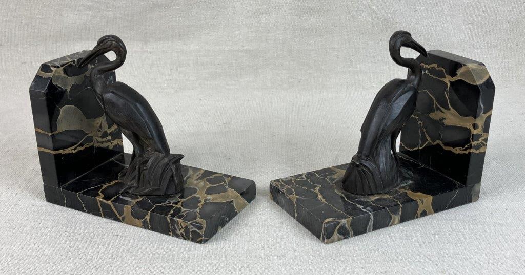 Pair of Crane Bookends: Pair of bookends featuring dark marble bases with soft gold veining, topped with cast metal crane figures. The combination of natural stone and sculptural metal creates an elegant decorative accent.