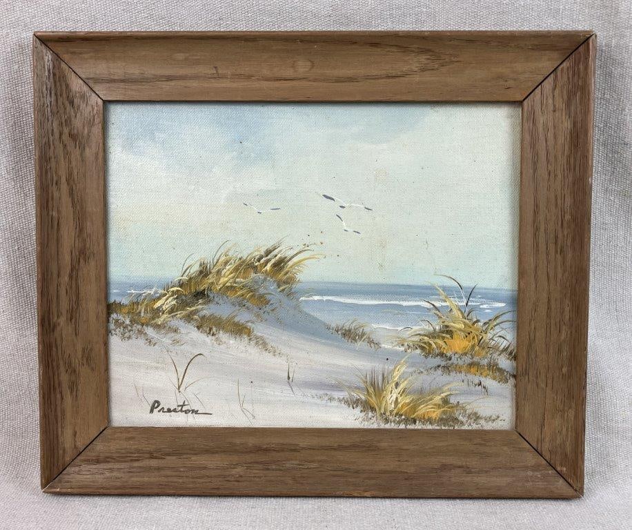 Beachscape Oil Painting: Oil painting depicting a coastal landscape with sand dunes, water, and seagulls, rendered with skillful attention to light and color. Housed in a wood frame. Frame measures approximately 10