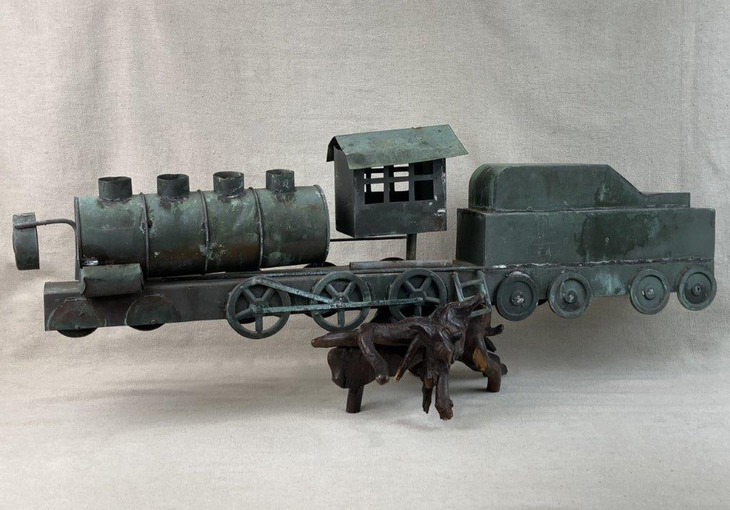 Folk Art Steel Train Sculpture: Hand-cut and welded steel train sculpture with a rich blue-green patina, mounted on a wood base, exhibiting strong folk art character and substantial presence. Measures approximately