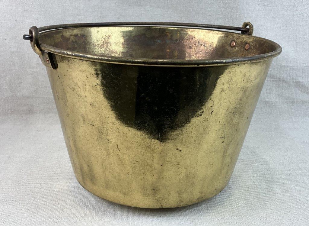 19th Century Brass Bucket with Wrought Handle: Antique brass bucket marked to the base with a company name, featuring a wrought iron handle and classic utilitarian form. Measures approximately 9â€³ H x 14 1/2â€³ in