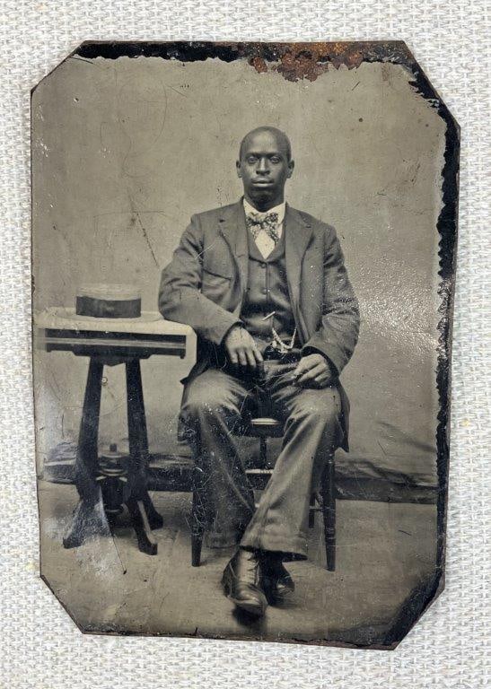 Black Americana Portrait Tintype: Ferrotype (tintype) portrait depicting an African American man in formal attire, reflecting period photographic practices and studio portraiture. Measures approximately 3 1/4" H x 2 3/8" W. General