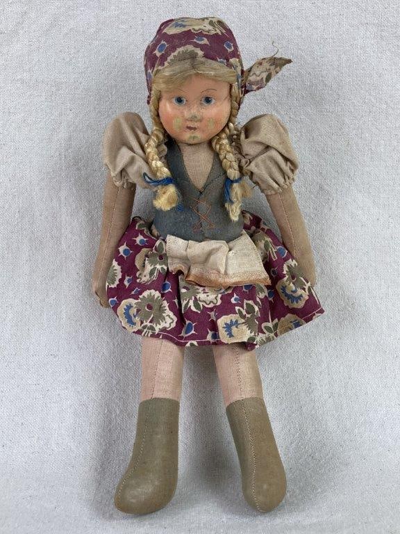 Polish Cloth Doll: This vintage Polish cloth doll is an authentic representation of Eastern European folk craft, featuring a saw-dust stuffed body and a delicately hand-painted celluloid face. Dressed in traditional