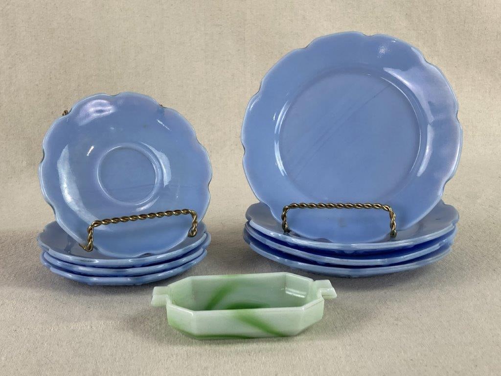 Cherry Blossom, Depresion Glass Group: A collection of nine glass tabletop pieces, including eight blue glass plates and a unique octagonal dish. The plates, consisting of four small and four larger examples, feature a distinct shaped rim