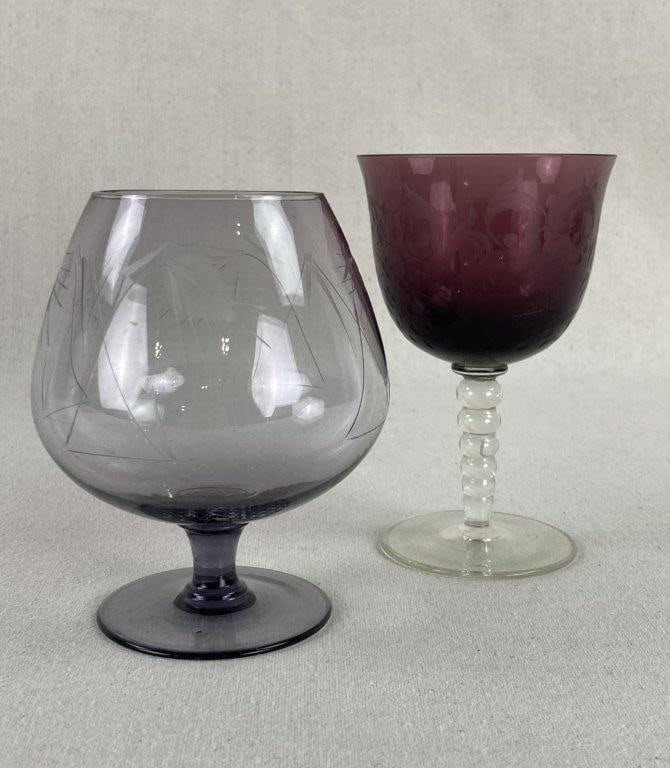 Etched Glass Drinking Vessels: This sophisticated duo of purple-hued vessels highlights the delicate artistry of American "elegant glass" from the mid-20th century, featuring a light amethyst brandy snifter adorned with flowing