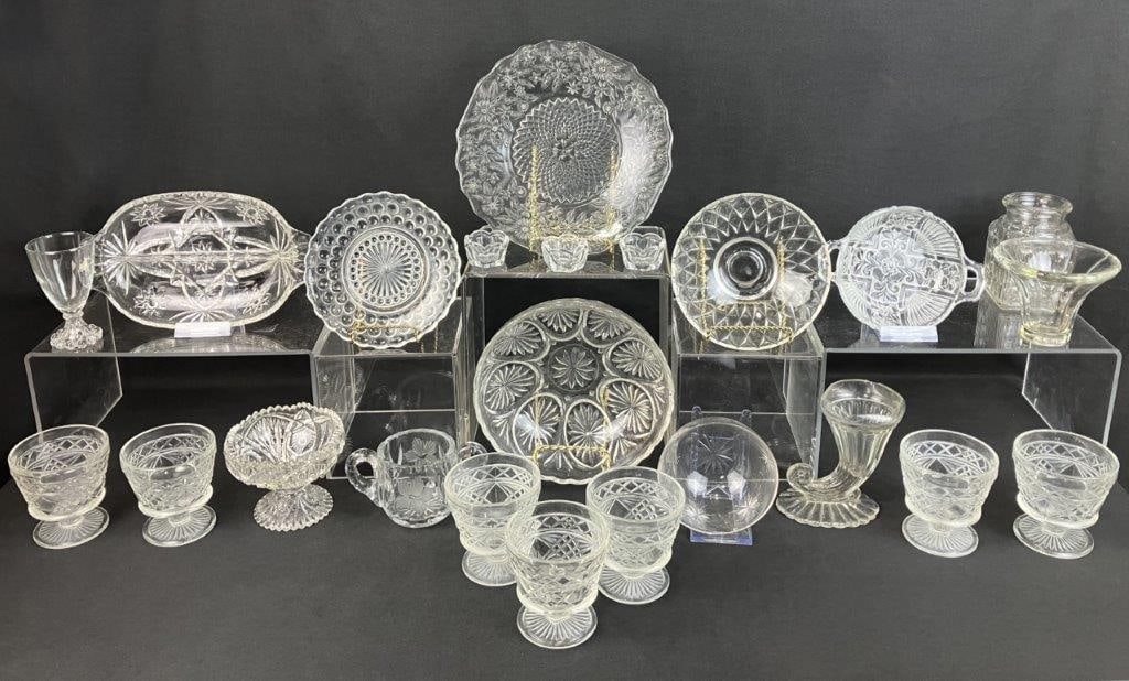 Pressed Glass Assortment: Assortment of twenty-three pieces of pressed glass in varied forms and sizes, displaying classic molded patterns. One measures approximately 1â€³ H x 9 1/4â€³ in diamet