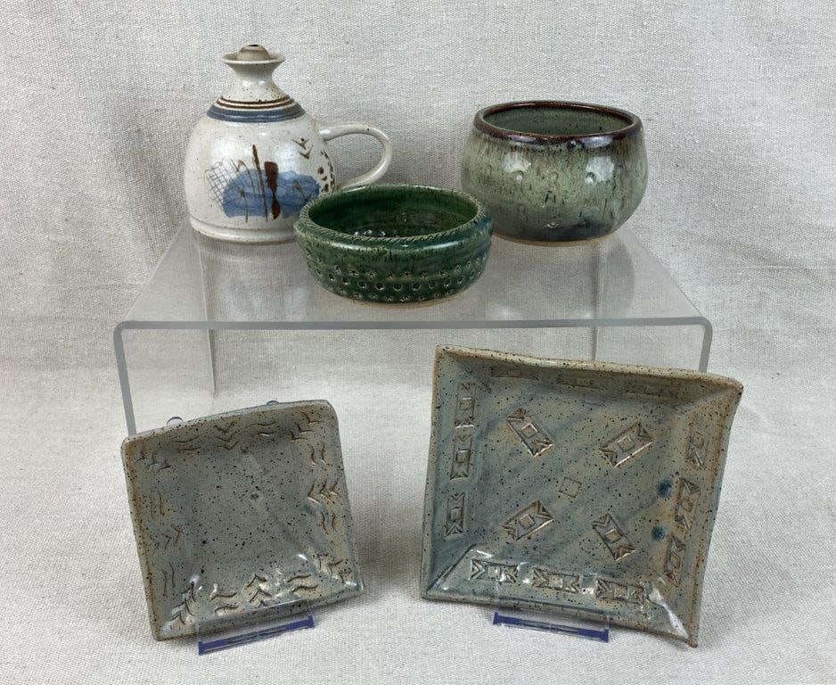 Studio Pottery Assortment: Group of five studio pottery pieces, some signed, featuring speckled earth-tone glazes. Two green bowls, two soft cool glazed speckled dishes, and a decorated jug. The jug measures approximately