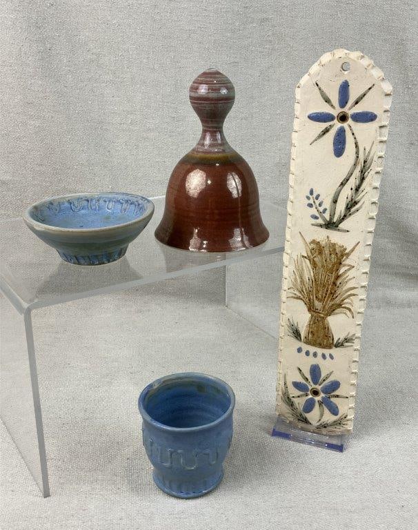 Studio Pottery Assortment: Group of four studio pottery pieces, some signed, featuring soft blue glazes alongside speckled earth-tone finishes. Includes decorated plaque, two blue vessels, and one bell. The bell measures