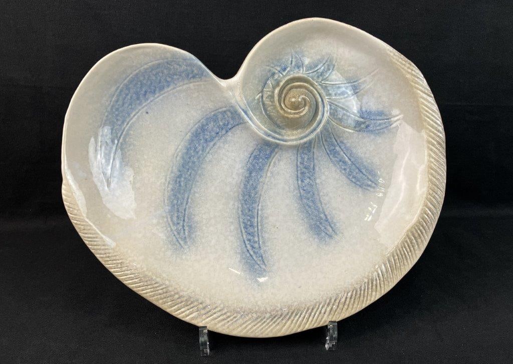 Ceramic Shell Plate: Ceramic plate modeled in the form of a nautilus shell, with light glazes and pale blue decoration. Measures approximately 2 1/8â€³ H x 12 5/8â€³ W x 9