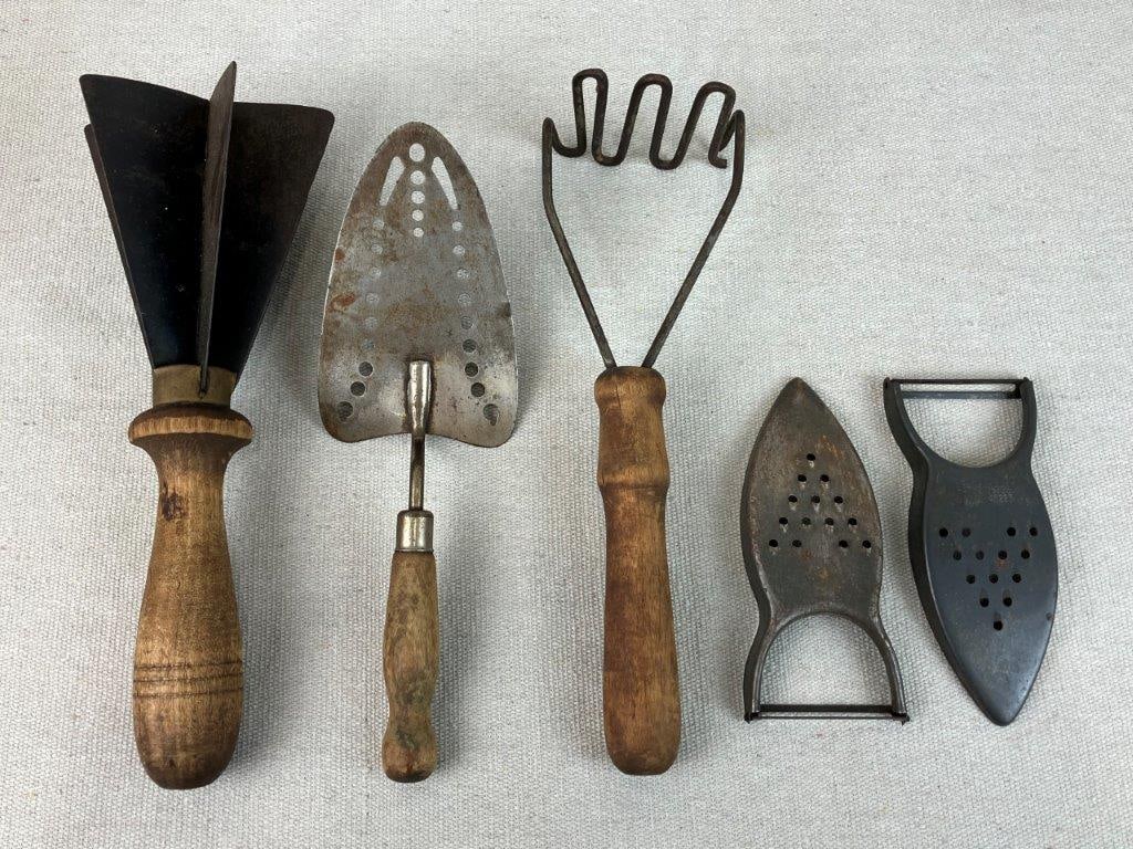 Primitive Cooking Utensils: Group of early kitchen utensils including a potato masher, a pie server, and additional pieces, each with wooden handles and rich patina to both metal and wood. The potato masher measures