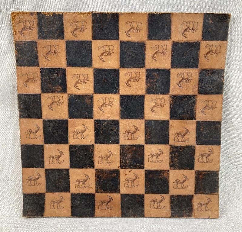 Tooled Leather Gazelle Checker Board: Tooled leather checkerboard featuring a gazelle motif within the lighter sections, displaying decorative craftsmanship and natural patina. Measures approximately 13 3/4â€³ H x 13