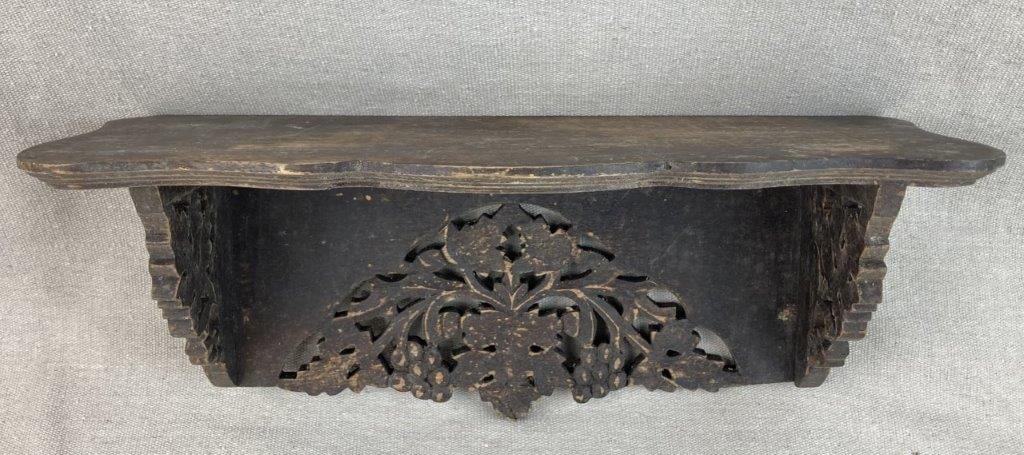 Small Carved Wood Shelf: A charming small wood shelf featuring intricate carvings along the back and sides, depicting a leaf and grape motif. The piece is designed with a shaped base and displays a worn, aged patina that
