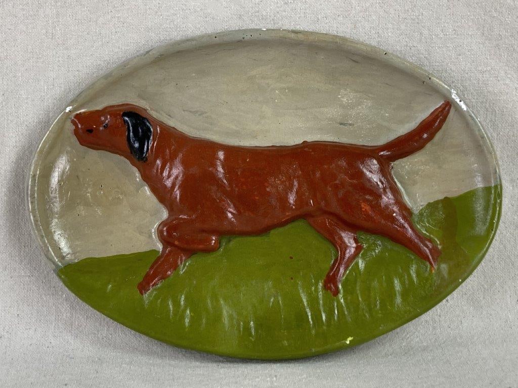 Folk Art Pointer Dog Plaque: A charming oval ceramic plaque featuring a raised relief of a brown painted pointer dog set against a rustic cream and green background. This folk-art piece captures a classic sporting dog silhouette
