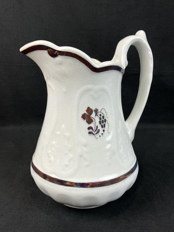 Decorated Ironstone Pitcher: Ironstone pitcher with embossed form and gilt tea leaf decoration, produced by Clementson Brothers. Measures approximately 10â€³ H x 7â€³ W x 5â€³ D.