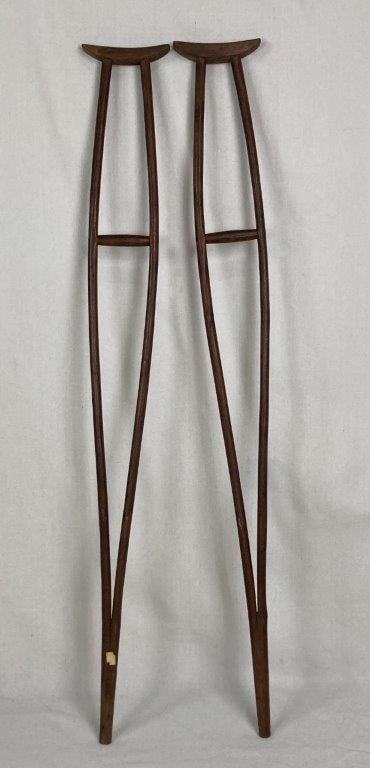 Pair of Oak Wood Crutches: Pair of antique hand-carved oak wood crutches with a rich, deep patina, exhibiting a rustic and utilitarian form. One measures approximately 54 1/2â€³ H x 7â€³ W x