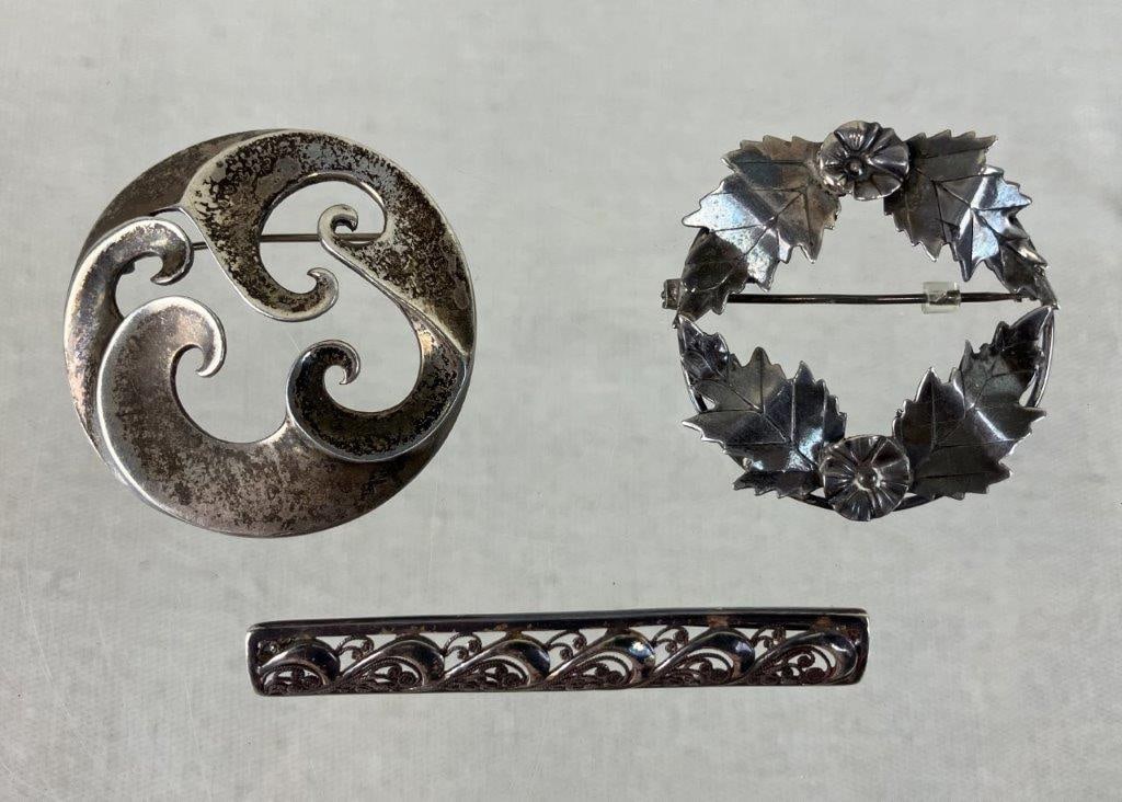 Vintage Sterling Silver Brooches Including MFA: A three-piece collection of vintage sterling silver brooches featuring a variety of classic and artistic designs. The assortment includes a circular wave-motif brooch by the Museum of Fine Arts,