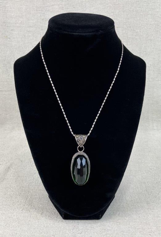 Sterling Silver Chrome Diopside Necklace: This sterling silver necklace features an intricate wire scrollwork pendant centered around a vibrant, faceted oval chrome diopside gemstone. The pendant hangs from a 16 in. sterling silver chain